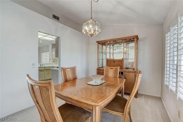 dining area with light carpet, lofted ceiling, and an inviting chandelier