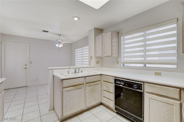 kitchen with sink, ceiling fan, light tile patterned floors, black dishwasher, and kitchen peninsula