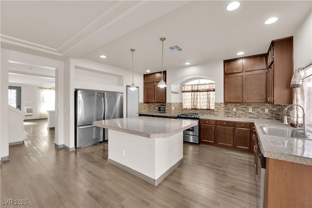 kitchen featuring a kitchen island, decorative light fixtures, sink, backsplash, and stainless steel appliances