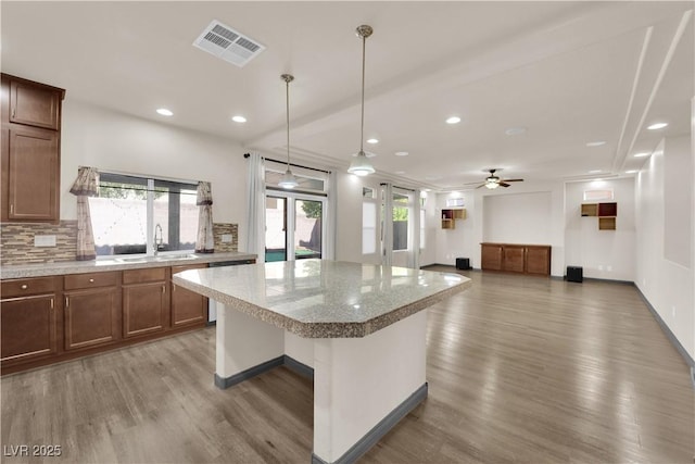 kitchen featuring sink, a kitchen breakfast bar, a kitchen island, pendant lighting, and hardwood / wood-style floors