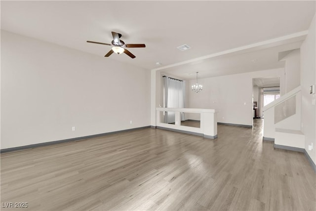 unfurnished living room featuring ceiling fan with notable chandelier and light hardwood / wood-style floors