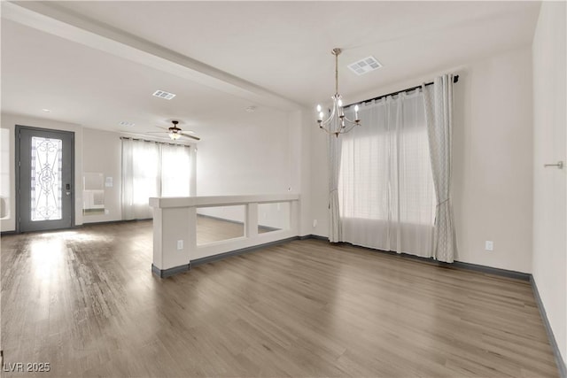 empty room featuring hardwood / wood-style flooring and ceiling fan with notable chandelier