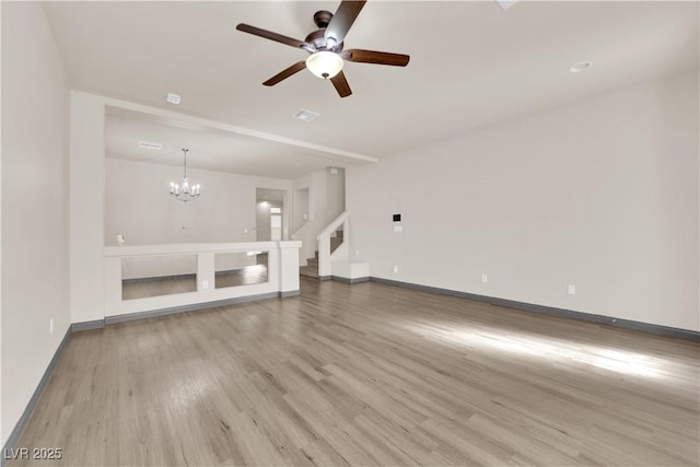 unfurnished living room with ceiling fan with notable chandelier and light hardwood / wood-style floors