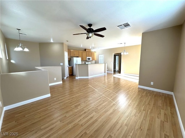 unfurnished living room featuring light hardwood / wood-style floors and ceiling fan with notable chandelier