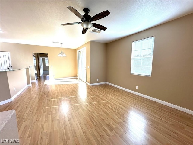 unfurnished room with a textured ceiling, ceiling fan with notable chandelier, and light hardwood / wood-style flooring