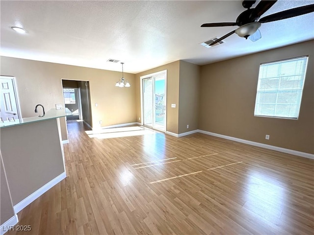 unfurnished room with sink, ceiling fan with notable chandelier, and light hardwood / wood-style flooring