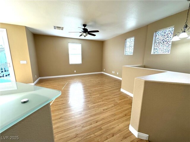 unfurnished room featuring ceiling fan with notable chandelier and light hardwood / wood-style floors