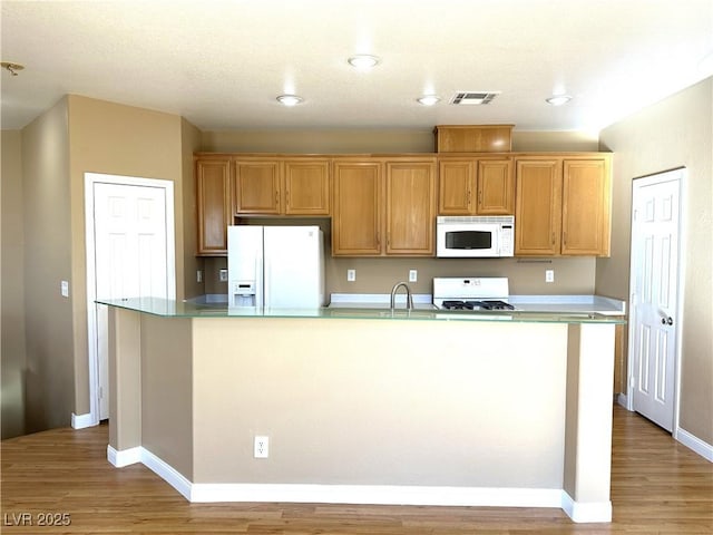 kitchen featuring white appliances, a center island with sink, and light hardwood / wood-style floors