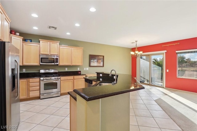 kitchen with a center island with sink, sink, light brown cabinetry, appliances with stainless steel finishes, and a notable chandelier