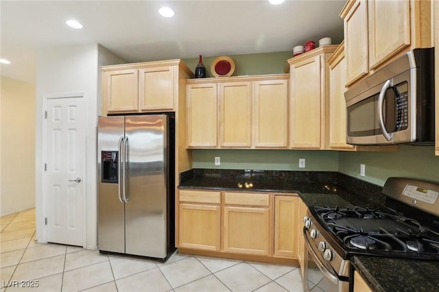 kitchen with dark stone countertops, light brown cabinets, and stainless steel appliances