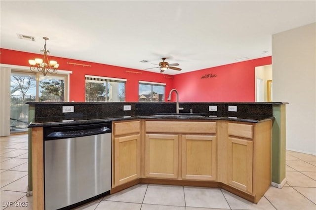 kitchen featuring ceiling fan with notable chandelier, stainless steel dishwasher, dark stone countertops, and sink