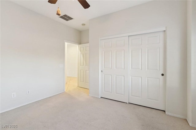 unfurnished bedroom featuring ceiling fan, a closet, and light carpet