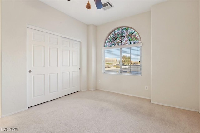 unfurnished bedroom featuring light colored carpet, a closet, and ceiling fan