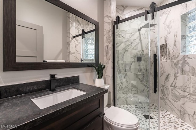 bathroom with toilet, a marble finish shower, and vanity