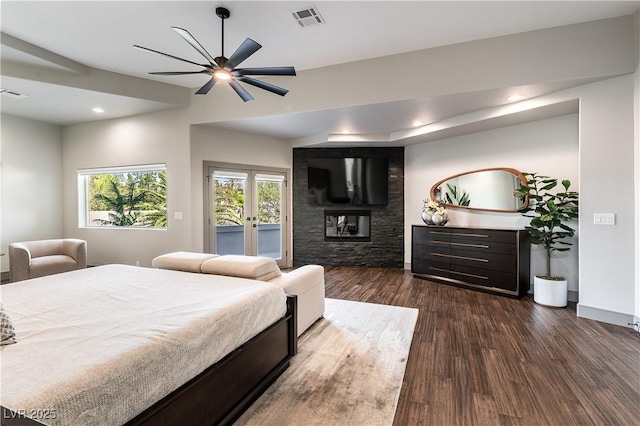 bedroom with dark wood finished floors, visible vents, access to outside, multiple windows, and a multi sided fireplace