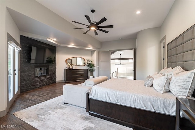 bedroom with recessed lighting, baseboards, a stone fireplace, and wood finished floors