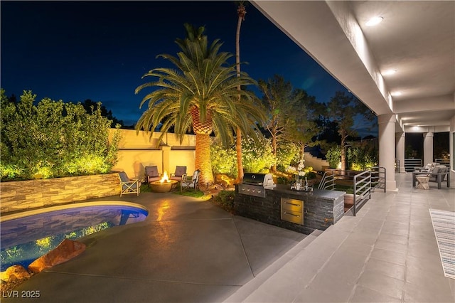 pool at twilight with area for grilling, exterior kitchen, an outdoor pool, a patio area, and a fire pit