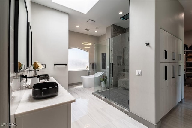 full bathroom featuring baseboards, a shower stall, a soaking tub, double vanity, and a skylight