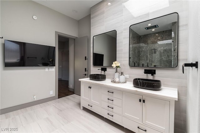 bathroom with double vanity and a marble finish shower