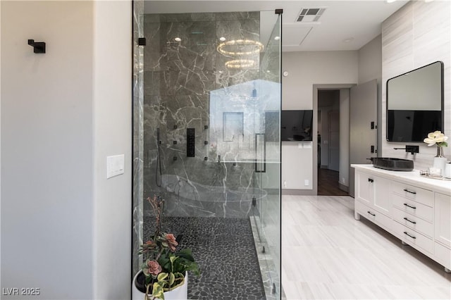 bathroom with a marble finish shower, an inviting chandelier, vanity, and visible vents