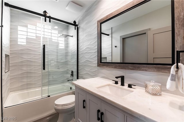 bathroom with tile walls, vanity, toilet, and bath / shower combo with glass door