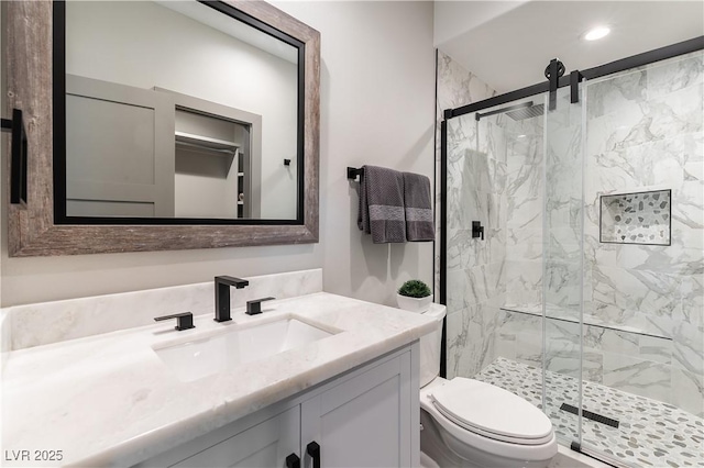 bathroom featuring toilet, a marble finish shower, vanity, and recessed lighting