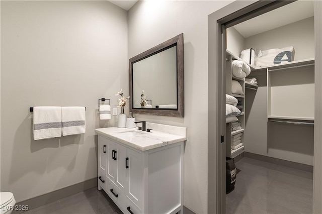 bathroom featuring toilet, tile patterned flooring, vanity, and baseboards