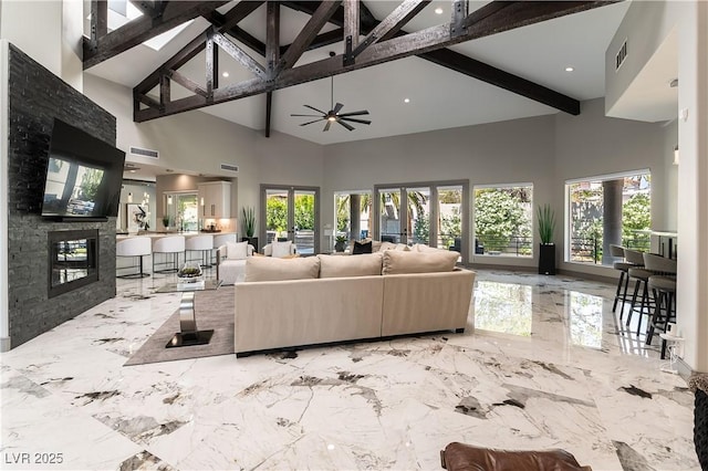 living room featuring french doors, beamed ceiling, a glass covered fireplace, and visible vents