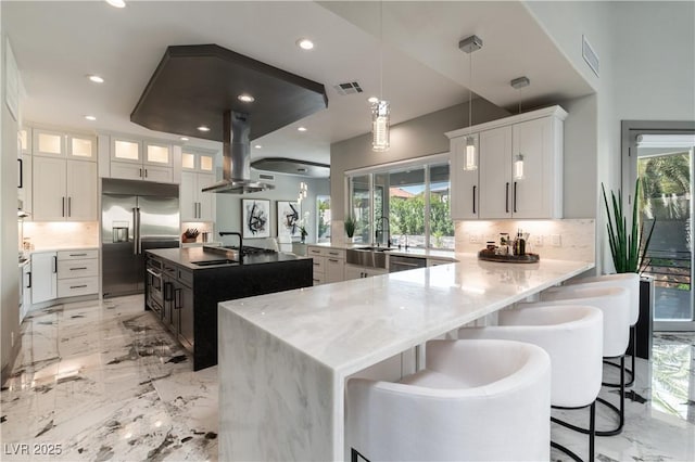 kitchen with visible vents, a sink, island range hood, backsplash, and appliances with stainless steel finishes