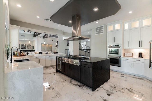 kitchen featuring appliances with stainless steel finishes, a sink, visible vents, and island range hood