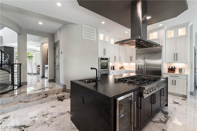 kitchen with recessed lighting, marble finish floor, a sink, island exhaust hood, and appliances with stainless steel finishes