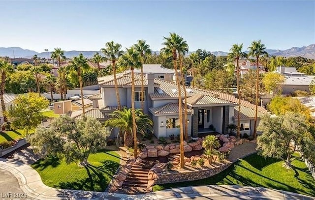 view of front of property featuring a front lawn, a tile roof, and a mountain view