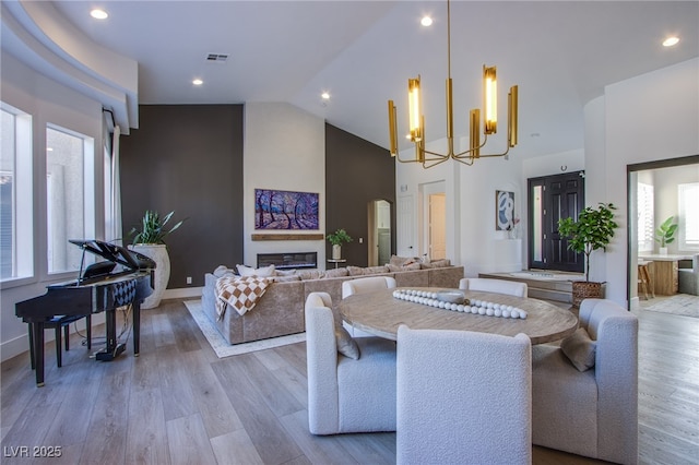 dining room featuring high vaulted ceiling, a chandelier, and light wood-type flooring