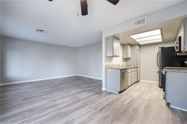 kitchen featuring gray cabinetry, ceiling fan, sink, stainless steel appliances, and light hardwood / wood-style floors