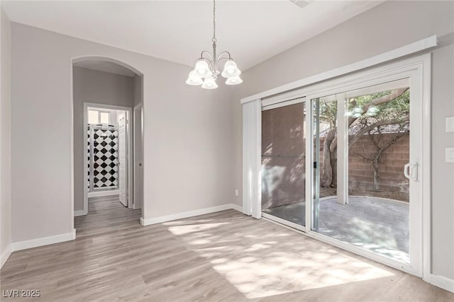 unfurnished dining area with a notable chandelier and wood-type flooring