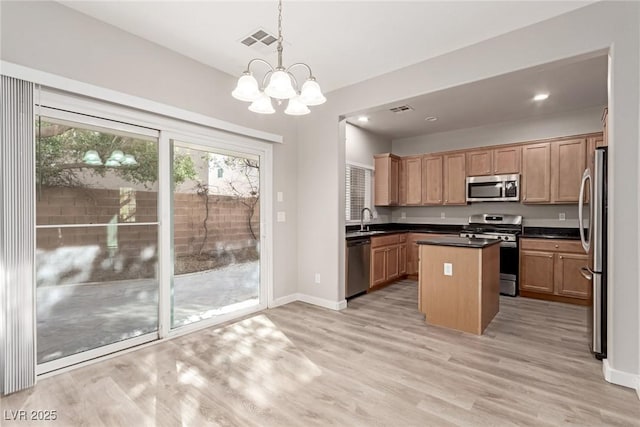 kitchen featuring appliances with stainless steel finishes, light hardwood / wood-style flooring, an inviting chandelier, a center island, and hanging light fixtures