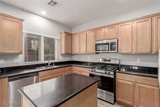 kitchen featuring a center island, sink, dark stone countertops, appliances with stainless steel finishes, and light hardwood / wood-style floors