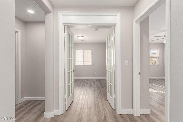 hall with french doors and light hardwood / wood-style floors