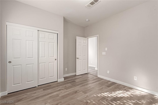 unfurnished bedroom with light wood-type flooring and a closet