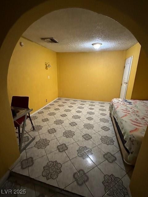 tiled bedroom with a textured ceiling