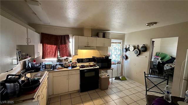 kitchen featuring light tile patterned flooring, sink, electric range, a textured ceiling, and cream cabinetry