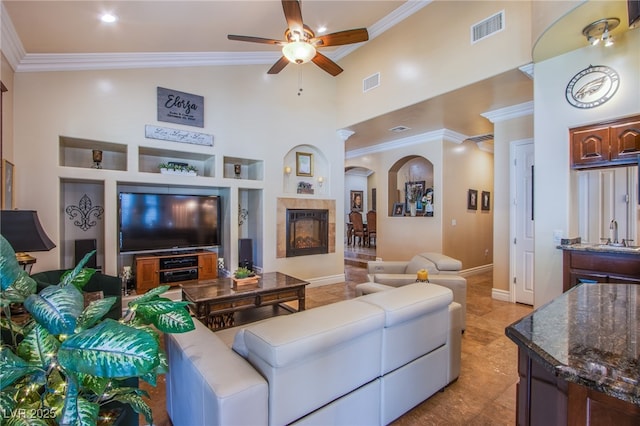 living room featuring built in shelves, sink, ceiling fan, light tile patterned floors, and a tiled fireplace