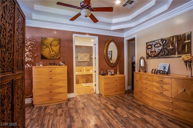 bedroom with crown molding, connected bathroom, ceiling fan, and a raised ceiling