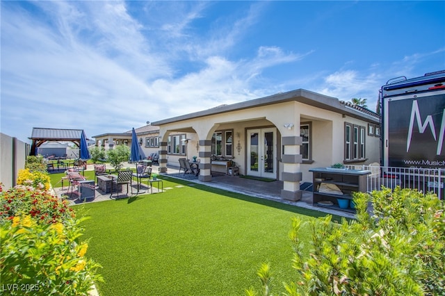 back of property with a lawn, a patio, and french doors