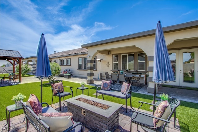 rear view of property featuring a patio, a gazebo, and an outdoor living space with a fire pit