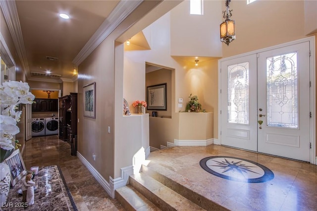 foyer with separate washer and dryer, crown molding, and french doors