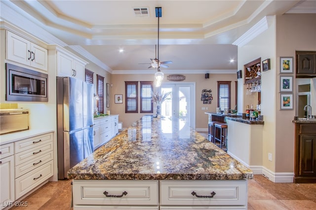 kitchen with crown molding, a center island, a tray ceiling, and stainless steel appliances