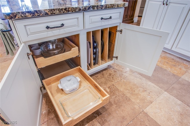 room details with dark stone countertops and white cabinetry