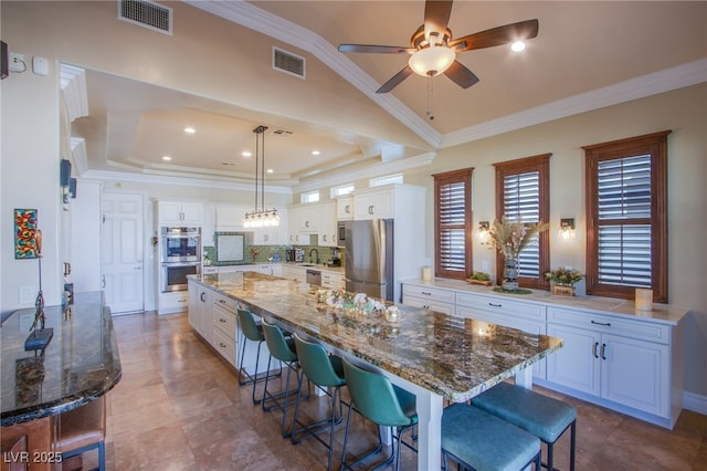 kitchen with decorative light fixtures, white cabinetry, a spacious island, and appliances with stainless steel finishes