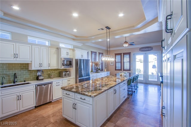 kitchen with white cabinetry, stainless steel appliances, a center island, and hanging light fixtures